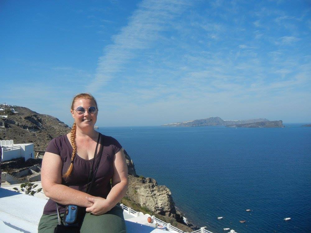 Samantha Hansen sitting on the edge of Santorini caldera in Greece